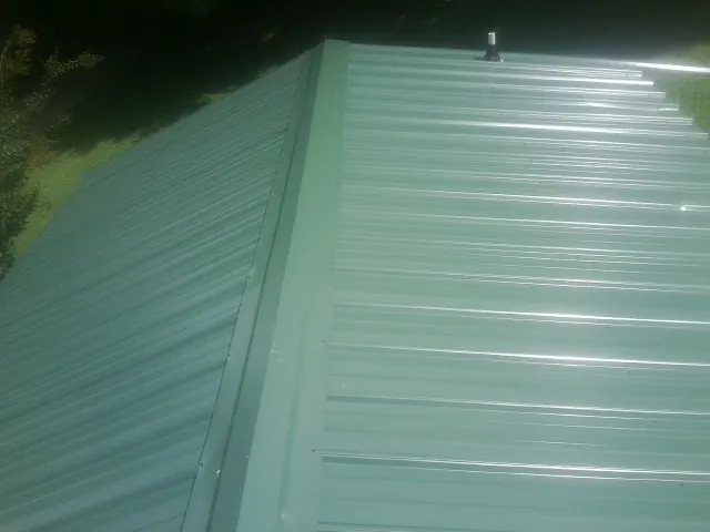 New green metal panels meeting at the ridge of a roof — Flat Roof Repair work by our crew in Woodstock