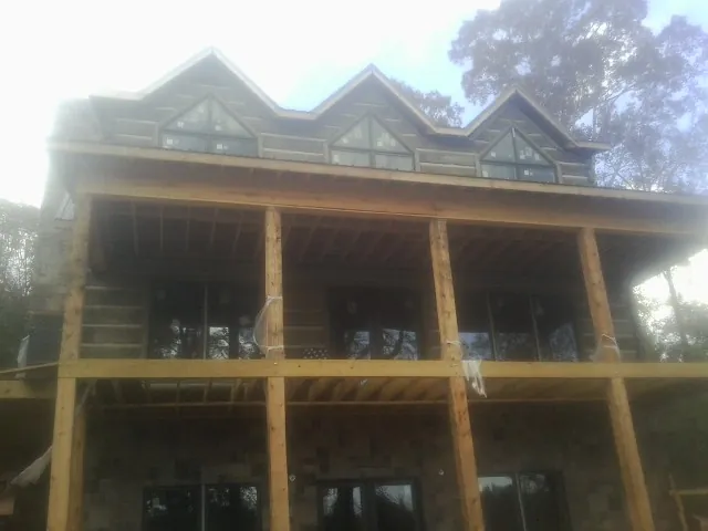 Dormers and porch framing on a large log home under construction — Roof Coating work by our crew in Woodstock