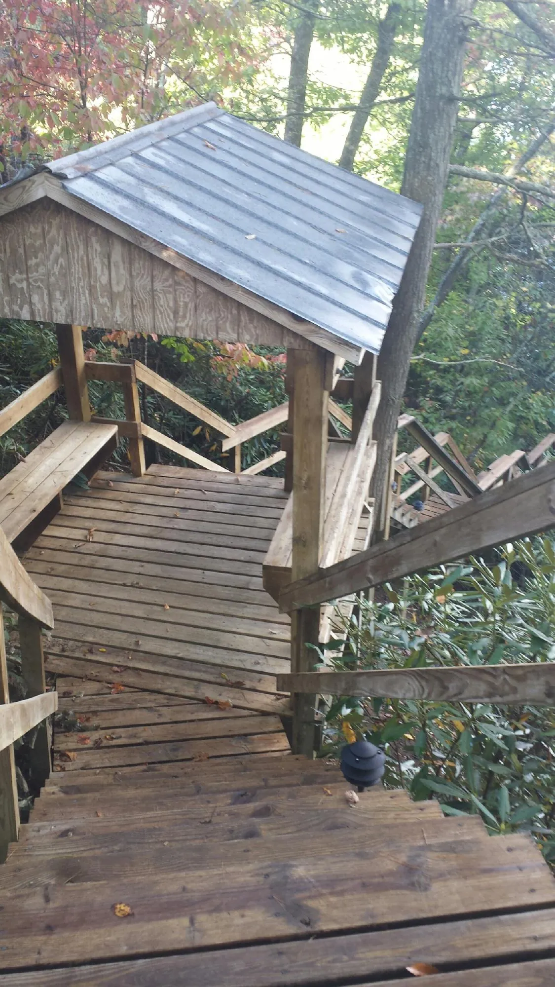 Metal roofed shelter over wooden steps on a wooded walkway — Skylight Repair & Installation work by our crew in Woodstock